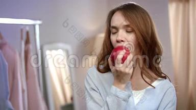 欢快的女人在家吃红苹果的肖像。 健康的女人吃水果